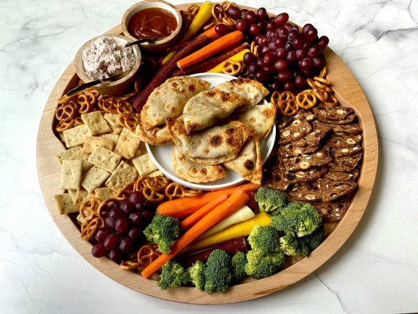 a round board with Pumpkin Empanadas, veggies, crackers, and dips