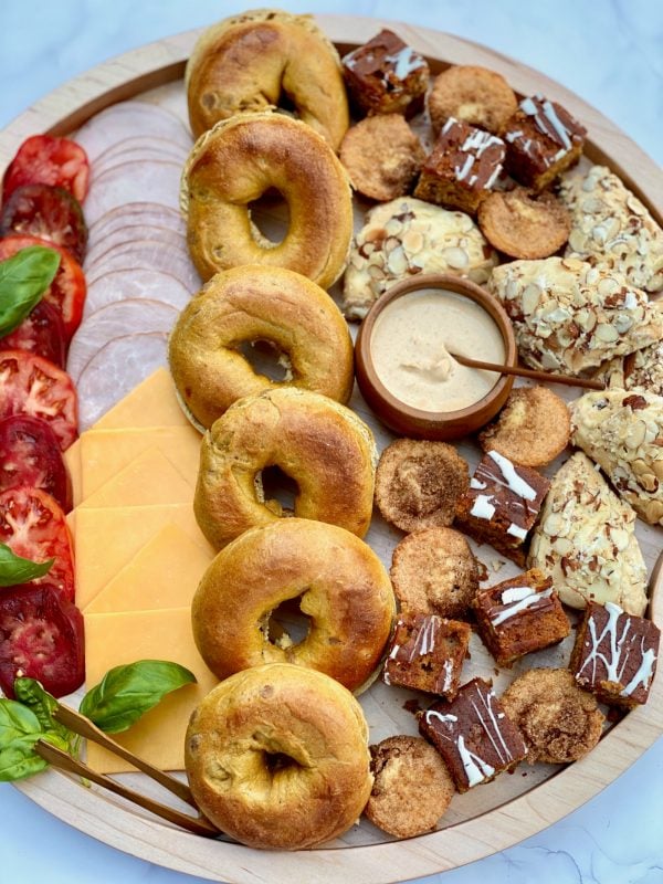 a round spread of pumpkin bagels, tomatoes, meat, cheesem and sweets