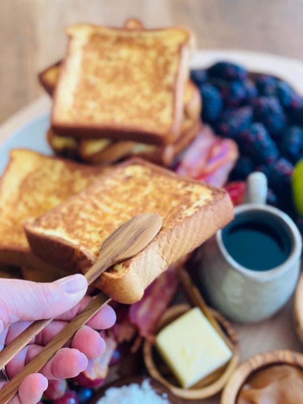 picking up a piece of brioche french toast with wood tongs