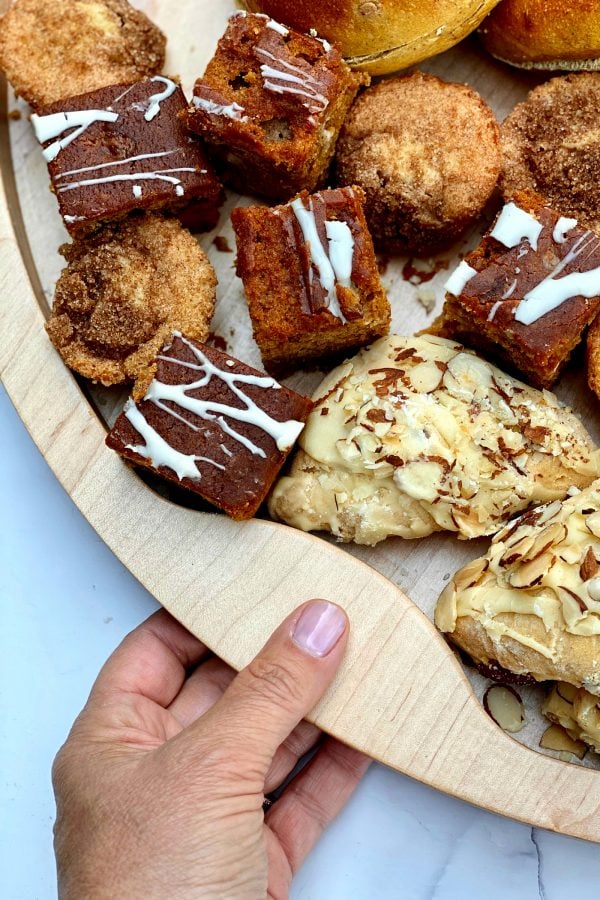 holding a wood board filled with breakfast scones