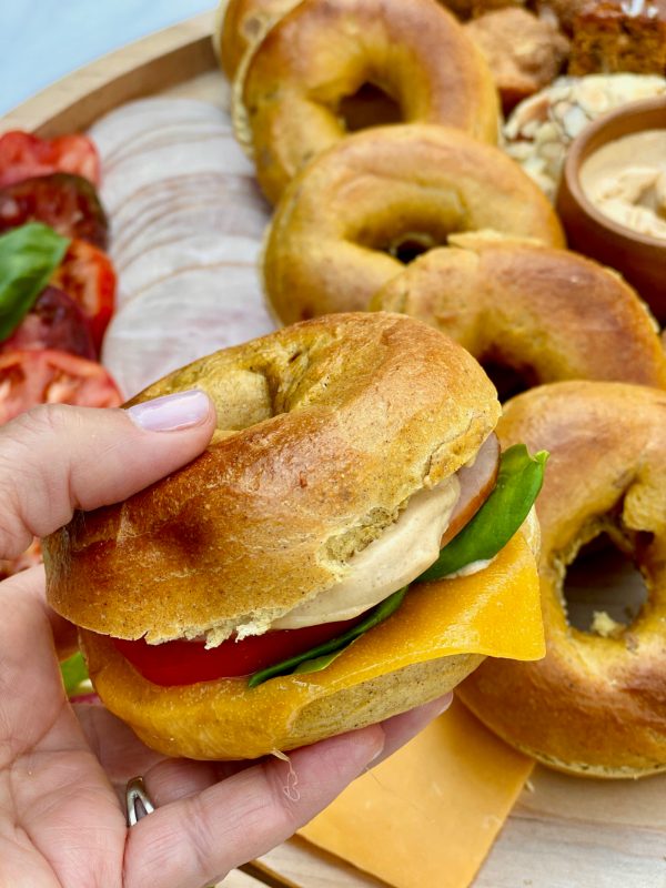 holding a pumpkin bagel breakfast sandwich