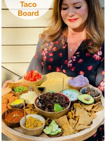 woman holding a round wood board with pumpkin spice taco ingredients