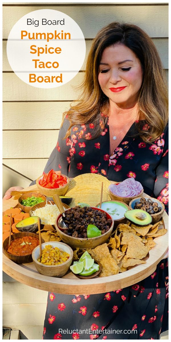 woman holding a round wood board with pumpkin spice taco ingredients