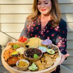 woman holding a round board with pumpkin taco ingredients