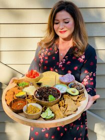 woman holding a round board with pumpkin taco ingredients