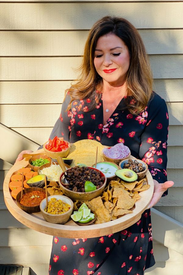 woman holding a round board with pumpkin taco ingredients