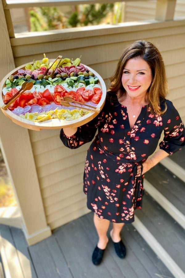 woman holding a large round board of burrata salad