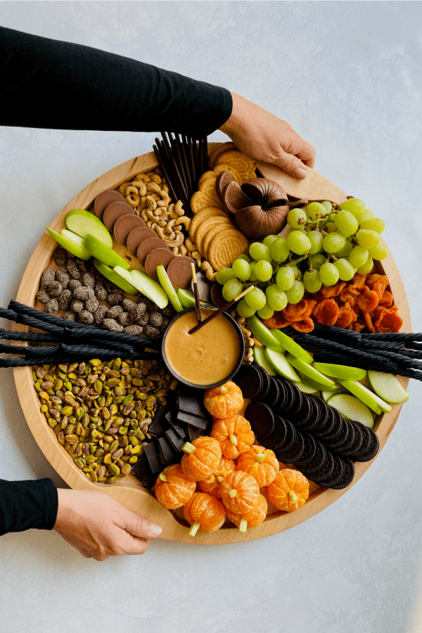 holding a round halloween snack board
