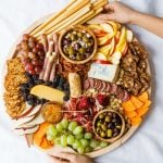 holding a round charcuterie board with winter snacks