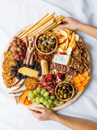 holding a round charcuterie board with winter snacks