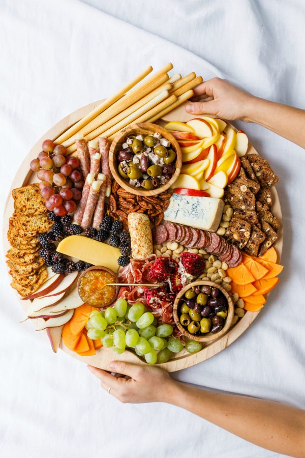 holding a round charcuterie board with winter snacks