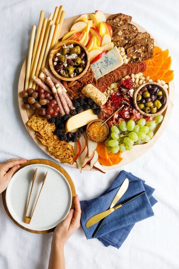 festive, winter round charcuterie board with plates and napkins