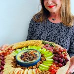 a woman holding a winter round charcuterie board