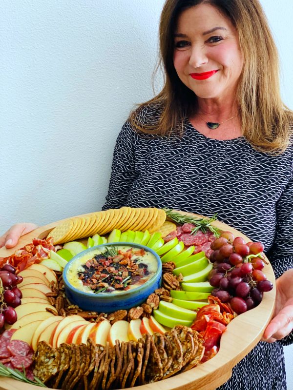 a woman holding a winter round charcuterie board