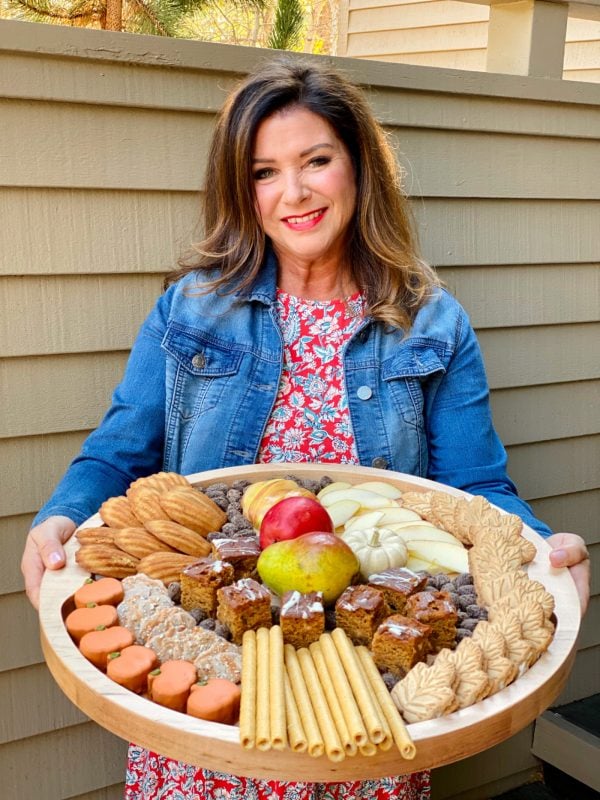 woman holding a round wood board with sweet fall snacks