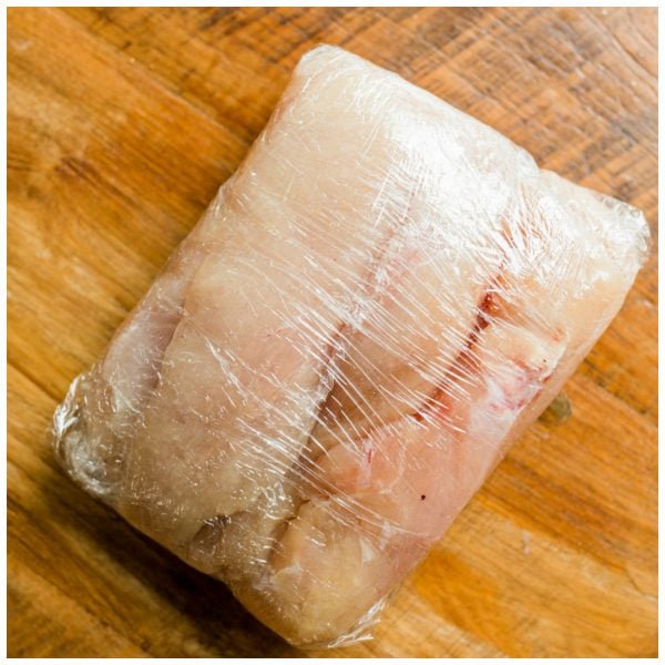 wrapping chicken in plastic wrap to prepare for cooking