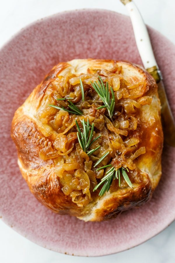 round of Onion Brie En Croute topped with fresh rosemary