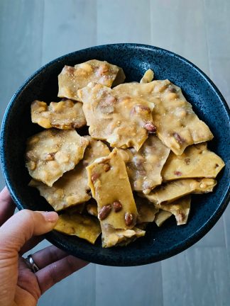 holding a black bowl of peanut brittle