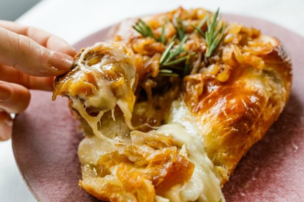 taking a cheesy bite of Onion Brie En Croute