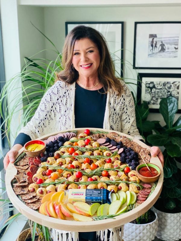 woman holding a large round tray of mini crescent dogs in a tree shop