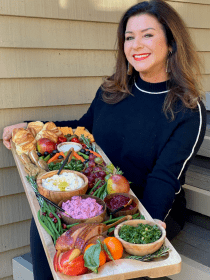 woman in black holding a holiday dinner board