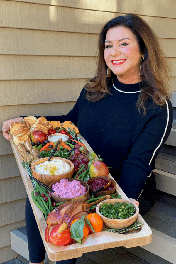 woman in black holding a holiday dinner board
