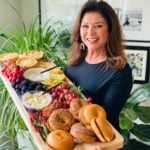 beautiful spread of brunch food on rectangle board tht woman is holding