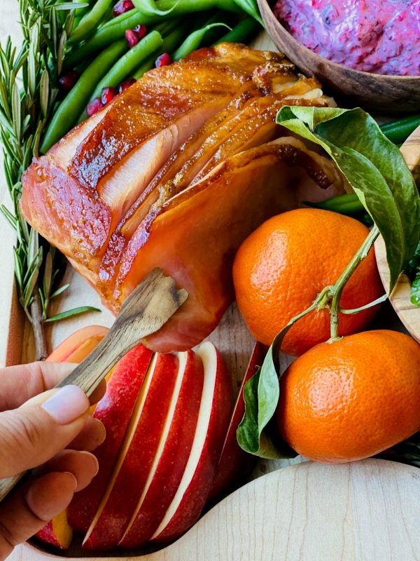 holding a piece of ham with wood tongs