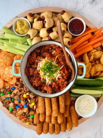 round board with pot of chili in center, surrounded by game day snacks