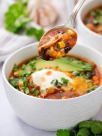 a spoonful of Slow Cooker Chicken Enchilada Soup garnished with avocado