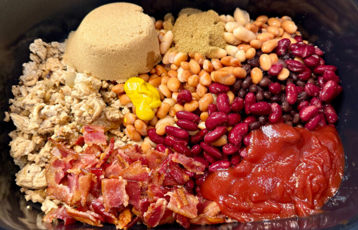 adding brown sugar and ingredients to beans