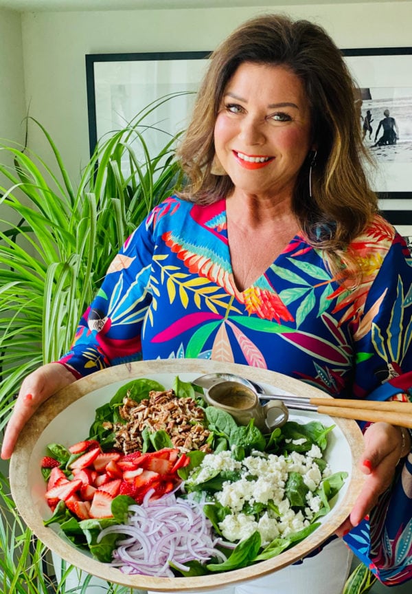 woman holding a large white bowl of My Favorite Strawberry Spinach Salad