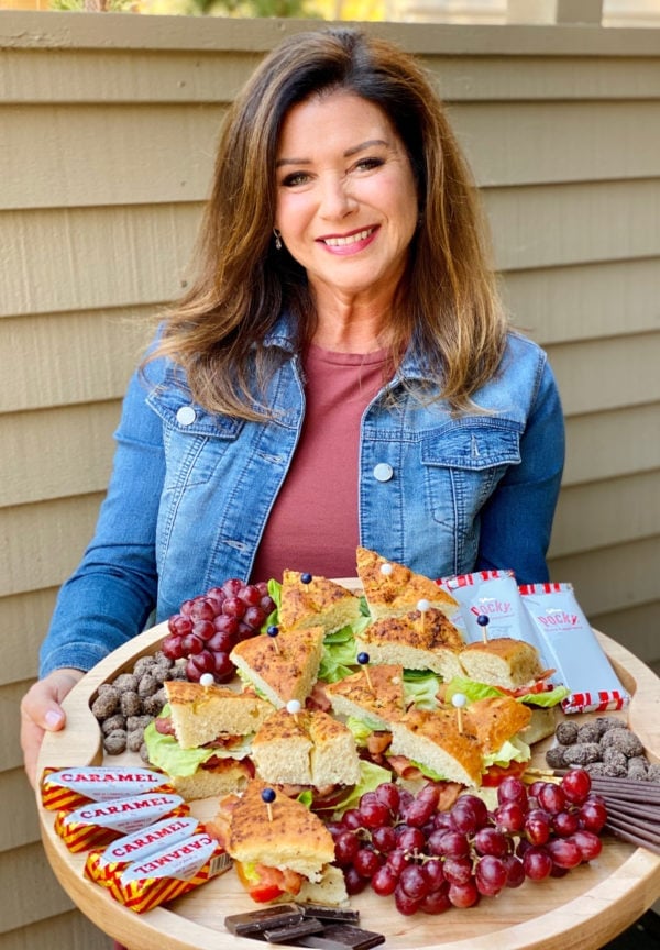 woman holding a BLT Focaccia Board with fruit and chocolate