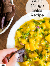 dipping a blue corn chip into mango salsa