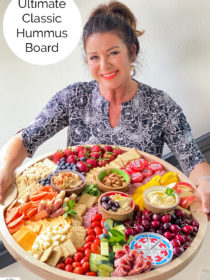 woman holding a round big board with hummus