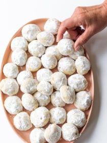 taking a Mexican Wedding Cookie off a plate