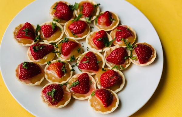 white plate of tarts with lemon and strawberries