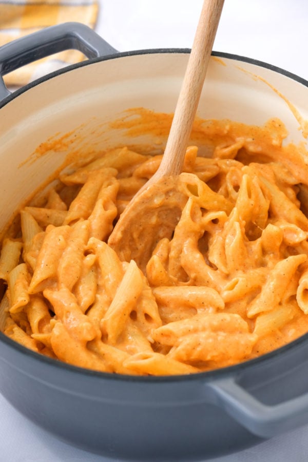 stirring pasta and paprika sauce in pan