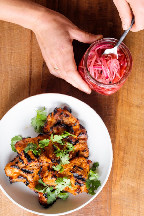 scooping out pickled red onions from jar