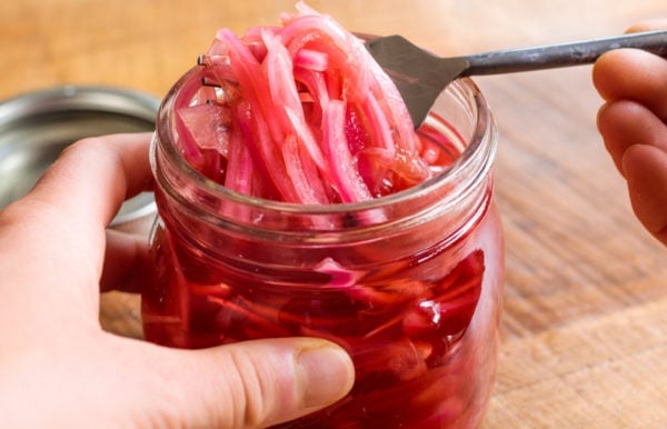 fork removing pickled red onions from jar