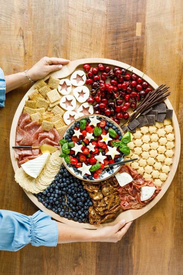holding a round blueberry patriotic charcuterie board