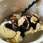 bowl of 2 scoops of banana ice cream with hot fudge