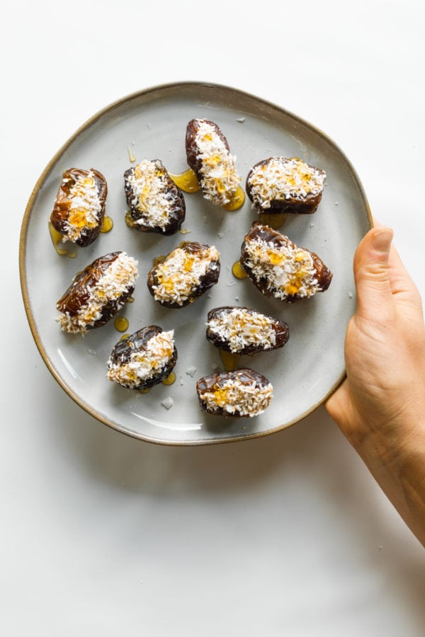 holding a plate of coconut stuffed dates