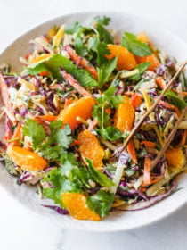 bowl of Crunchy Cashew Cabbage Salad with tongs