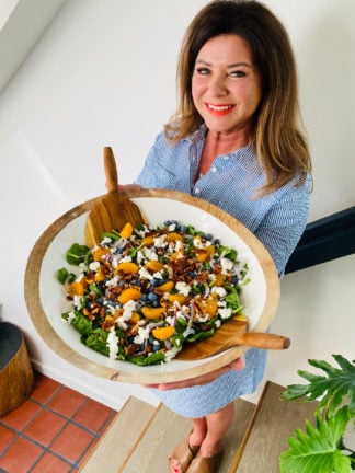 woman holding big white bowl spinach salad
