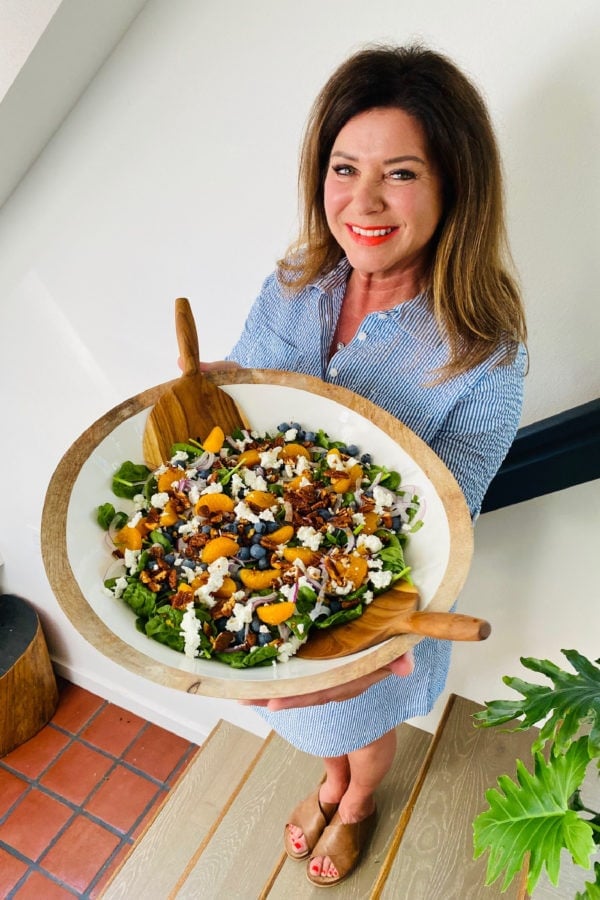 woman holding big white bowl spinach salad