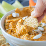 dipping Triscuit cracker into pumpkin hummus