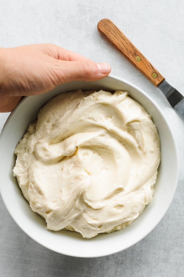 holding a bowl of Cream Cheese Mascarpone Frosting