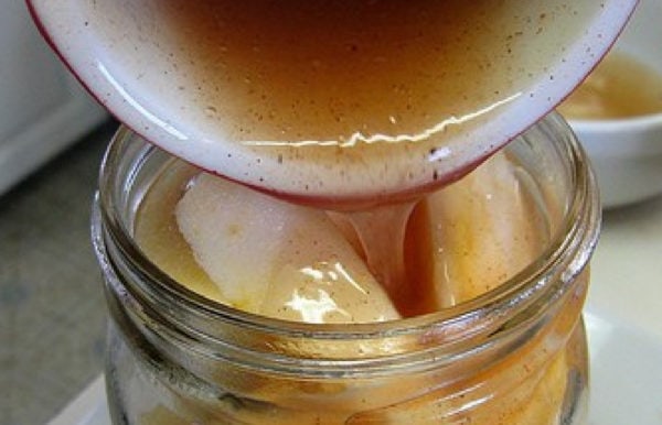 pouring filling over apples in a jar