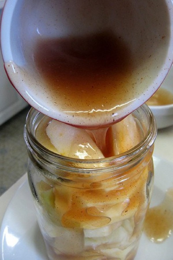 pouring filling over apples in a jar